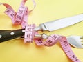 Knife and measuring tape cutlery losing measurement rolled on a colored background