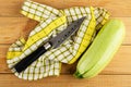 Knife on napkin, ripe marrow squash on wooden table. Top view