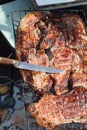 Knife on a piece of fried meat on a metal grill