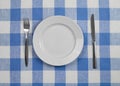 Knife, plate and fork checked tablecloth top view