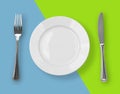 Knife, plate and fork on color backdrop top view
