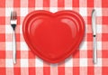 Knife, plate in heart shape and fork on tablecloth Royalty Free Stock Photo