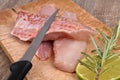 Knife on raw red mullet fillets laid on a cutting board with a slice of lemon and rosemary close-up