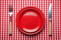 Knife, red plate, and fork on red checked tablecloth Royalty Free Stock Photo