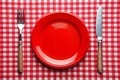 Knife, red plate, and fork on red checked tablecloth Royalty Free Stock Photo