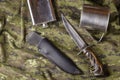 Knife, scabbard, metal flask and mug on camouflage fabric Royalty Free Stock Photo