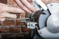 Knife sharpener and hand with blade on wooden table, closeup Royalty Free Stock Photo