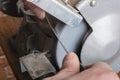 Knife sharpener and hand with blade on wooden table, closeup Royalty Free Stock Photo