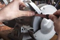 Knife sharpener and hand with blade on wooden table, closeup Royalty Free Stock Photo