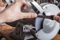 Knife sharpener and hand with blade on wooden table, closeup Royalty Free Stock Photo