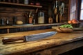 knife and sharpening stone on a rustic wooden table with kitchen background Royalty Free Stock Photo