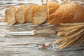 Knife sliced bread wheat ears on wooden surface Royalty Free Stock Photo