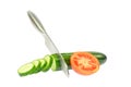 The knife sliced cucumber into slices next to a half tomato