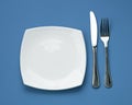 Knife, square plate and fork on blue top view