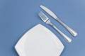 Knife, square plate and fork on blue top view