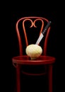 Knife stuck on a white cabbage put on a Thonet chair