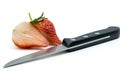 Knife with two halves of a sliced strawberry on a white background. Royalty Free Stock Photo