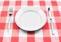 Knife, white plate and fork on checked tablecloth