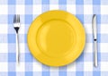 Knife, yellow plate and fork on checked tablecloth