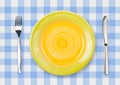 Knife, yellow plate and fork on checked top view Royalty Free Stock Photo
