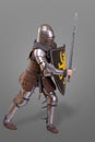 Knight in breaths in a helmet with a sword and shield in battle over grey background Royalty Free Stock Photo