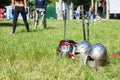 Knightly helmets lie on the grass against the background of sword-fighting people