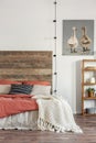 Knit blanket on a bed with wooden bedhead standing against white wall with an oil painting of ducks. Real photo of bedroom Royalty Free Stock Photo