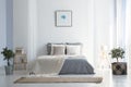 Knit blanket on grey bed in bright bedroom interior with poster