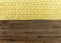 Knited yellow fabric.braid pattern on the wooden background.