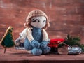 Knitted angel, amigurumi toy sits next to a jar of jam