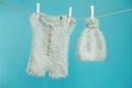 Knitted baby clothes drying on washing line against turquoise background Royalty Free Stock Photo