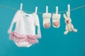 Knitted baby clothes and handmade toy drying on washing line against turquoise background Royalty Free Stock Photo