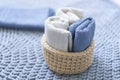Knitted basket of light color with towels on blue background