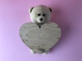Knitted bear with a heart made of wood. cute gift on a pink background. an engagement gift. handmade bear of threads, crocheted Royalty Free Stock Photo