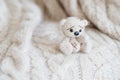 Knitted beige bear sits on a plaid of handmade