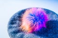 Knitted beret with a bright colorful artificial fur pompom