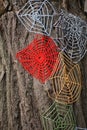 Knitted cobweb with colored threads on a tree trunk