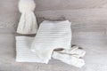 Knitted cold weather accessory on the table. White hat, scarf ant gloves grey wooden background. Top view. Copy space. Royalty Free Stock Photo