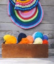 Knitted colorful striped mats and balls of bright woolen yarn in a wooden box on old wood wall background Royalty Free Stock Photo