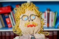 Knitted and crocheted male doll with mustache, glasses, blue eyes and blond curly hair. Close-up portrait.