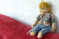 Knitted and crocheted male doll in the shape of a blond man with a mustache, curly hair, glasses, jeans and checked shirt.