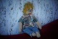 Knitted and crocheted male doll in the shape of a blond man with a mustache, curly hair, glasses, jeans and checked shirt.