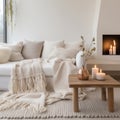 Knitted fringed blanket on white sofa, wooden coffee table with candles on carpet near it. Scandinavian, hygge interior design