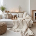 Knitted fringed blanket on white sofa, wooden coffee table with candles on carpet near it. Scandinavian, hygge interior design