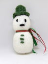 Knitted snowman child`s toy with green hat and ribbon scarf isolated on white background Royalty Free Stock Photo