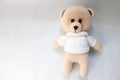 A knitted homemade beautiful cute little bear in a white sweater with black eyes, a soft toy tied with beige large threads on a li Royalty Free Stock Photo