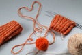 Knitted items with knitting needles and yellow threads, a heart made of yarn on a gray background, top view-the concept of Royalty Free Stock Photo