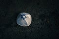 knitted kippah cap in Israeli flag style on a dark asphalt road background