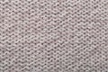 Knitted natural wool light brown surface as background.Close up.Concept for knitting cozy sweaters, warm winter knitted clothes