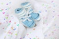 Knitted newborn baby booties on crocheted blanket white background with colorful hearts Royalty Free Stock Photo